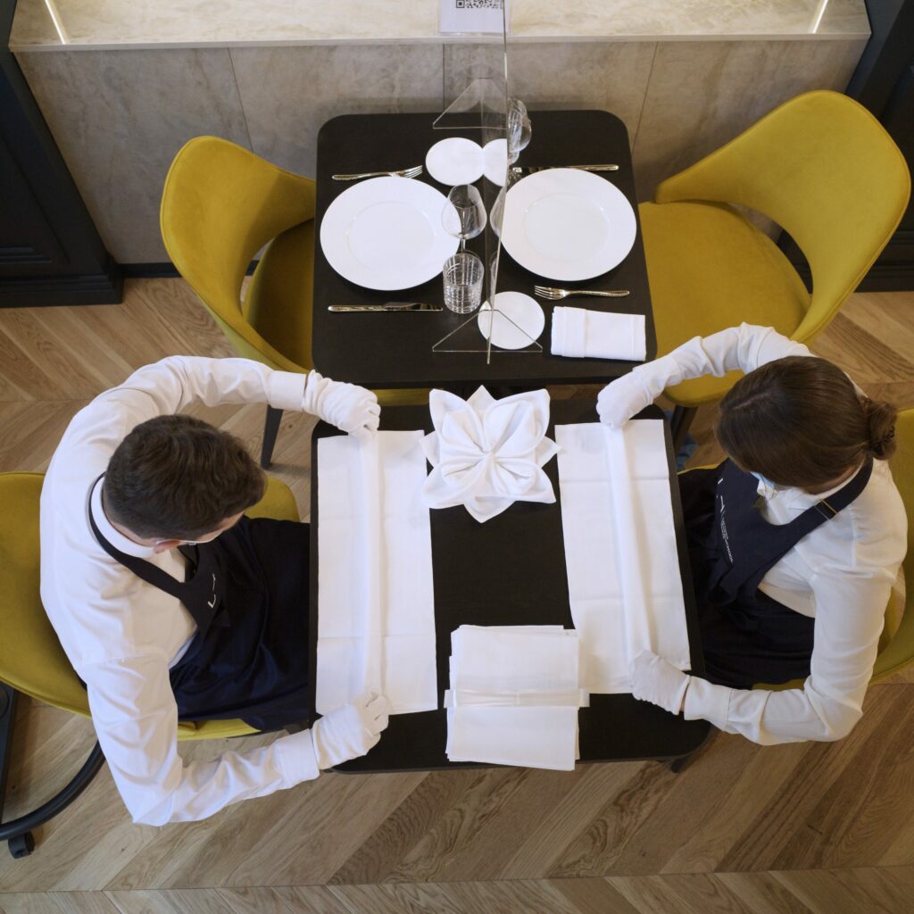 Photo vu du haut de deux étudiants qui dressent une table - Luxury Hotelschool
